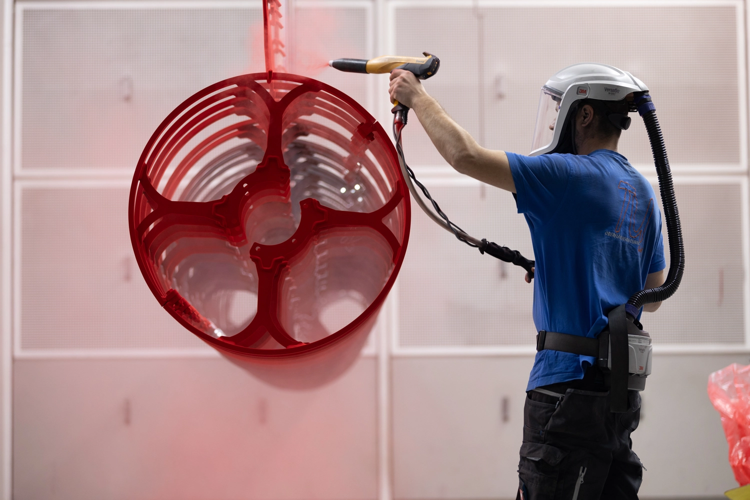 OZR GmbH - Oberflächenzentrum, industrielle Pulverbeschichtung - Ein Mann, der eine rote Pulverbeschichtung anbringt