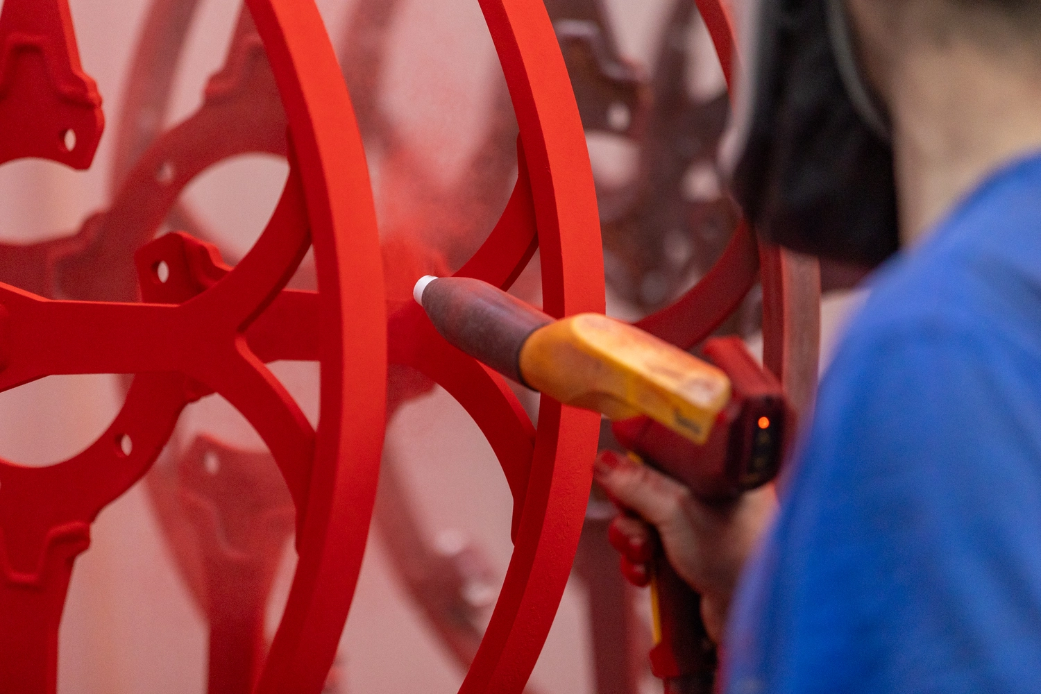 OZR GmbH - Oberflächenzentrum, industrielle Pulverbeschichtung - Ein Mann, der eine rote Pulverbeschichtung anbringt